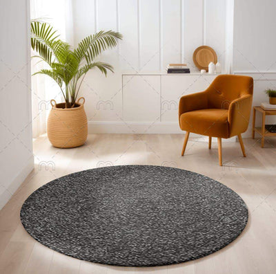 Round alfombra sensación carpet in dark gray antracita tone in modern living room with tan armchair and potted plant