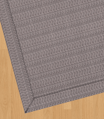 Alfombra de vinilo tejido premium en diseño trenzado sobre suelo de madera.